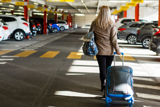 A girl with bag in the parking at the airport.