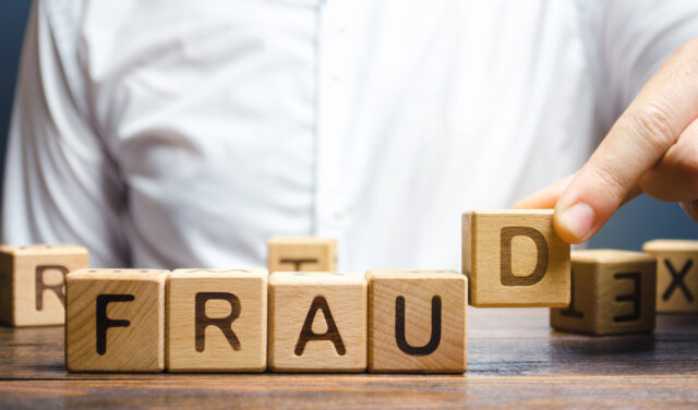 Wooden blocks with the word Fraud and man, Scam.