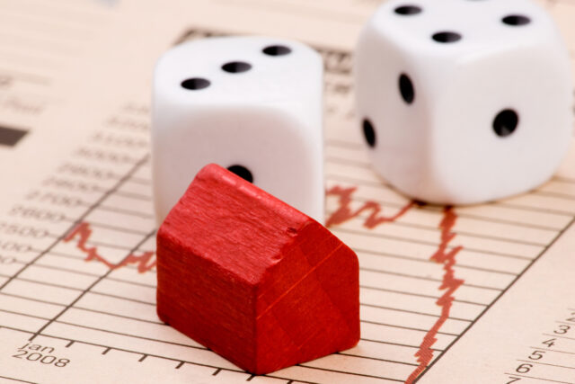 Housing market concept image with graph and toy house with dice, representing gambling.