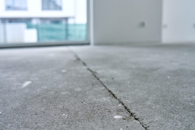 Close-up of cracked concrete floor in unfinished interior during repair works representing surveyor neglgience