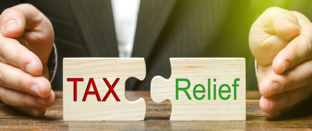 A businessman puts two puzzles with the words Tax and Relief