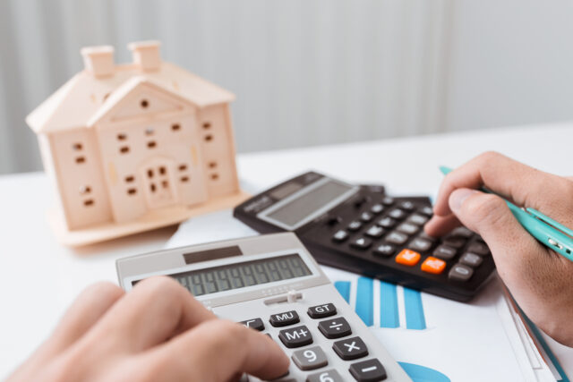 Calculator, house model, and paperwork symbolising surveyor negligence claim calculations