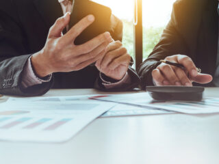 Solicitor’s hand reviewing debt paperwork with calculator.