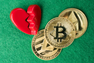 Gold physical Bitcoin, Litecoin and Ethereum coins with broken heart on green background representing crypto romance scams.