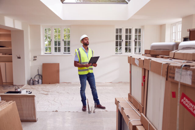 Surveyor inspecting property with clipboard in hand inside residential building