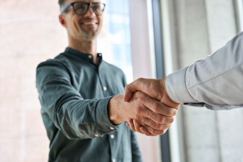 Two men shaking hands at office meeting— symbolising communication and the stages of protocol.