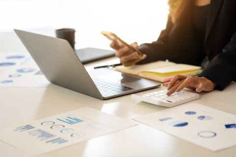 Close-up of hands examining spreadsheets and calculator
