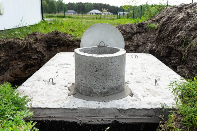 Concrete septic tank with a capacity of 10 cubic meters placed in the garden by the house, visible water below.