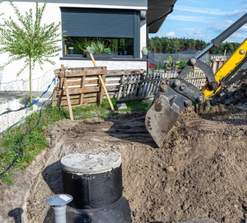 Hidden septic tank or ground near country home conveying the unseen septic tank problem and potential property liabilities discovered post-purchase.