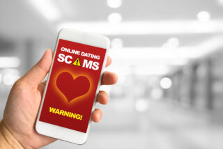A woman hand holding smartphone against white grey bokeh abstract background online dating scams concept.