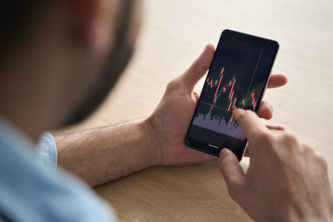 Fake crypto trading app on smartphone representing cryptocurrency romance scams.