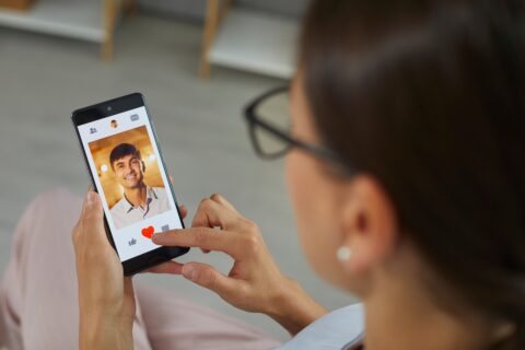 Person viewing overly attractive dating app profile, symbolising romance scam initiation.