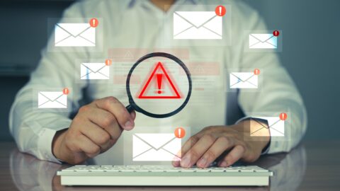Suspicious phishing email on a laptop highlighting mis-spelt sender address and fraudulent links