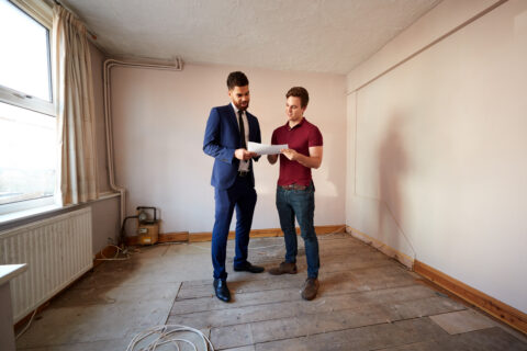 Homebuyer discussing property survey findings with a surveyor inside a UK house