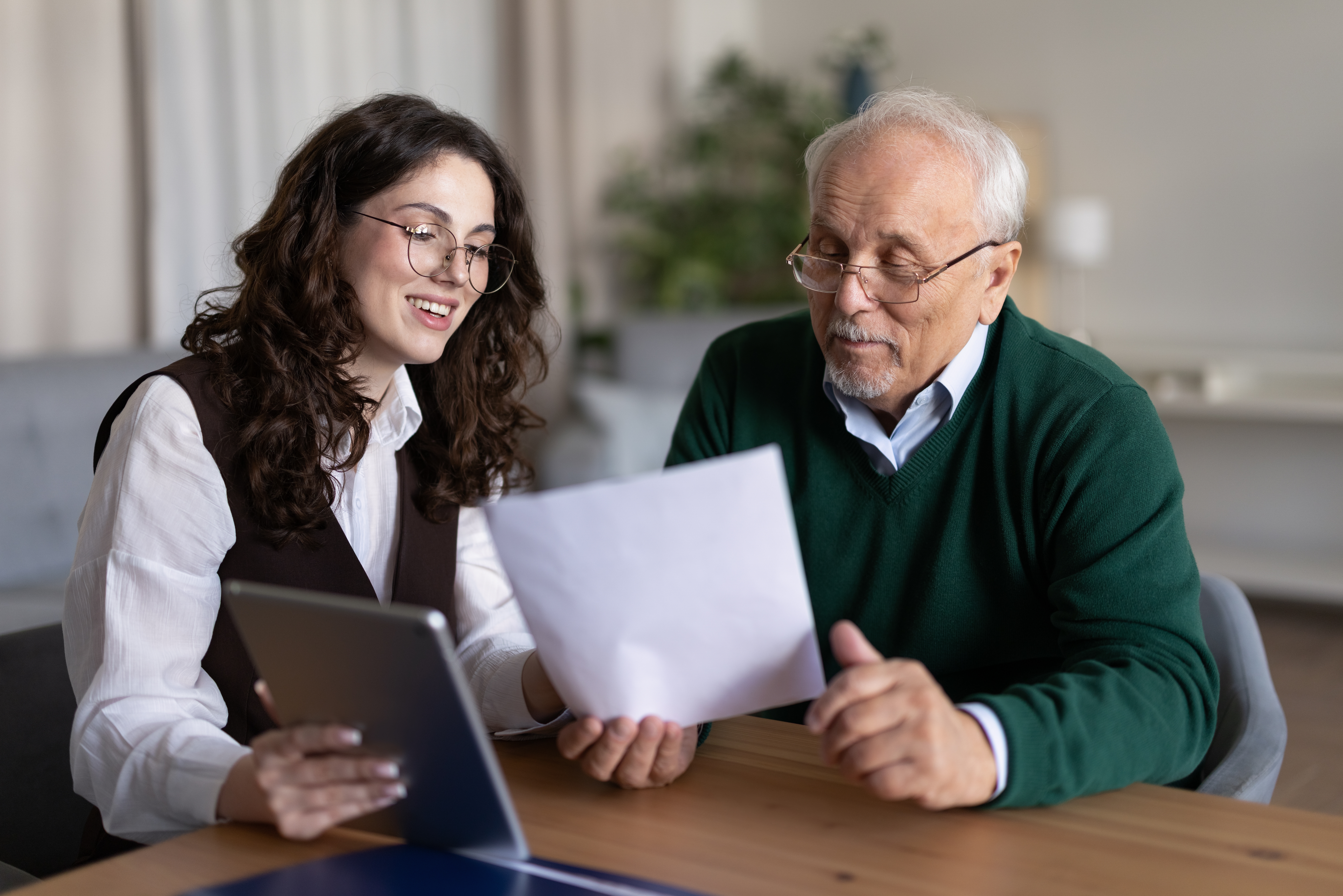 An older adult reviews a financial statement at home with a concerned expression, reflecting the point at which someone may begin to question pension advice years after a transfer.